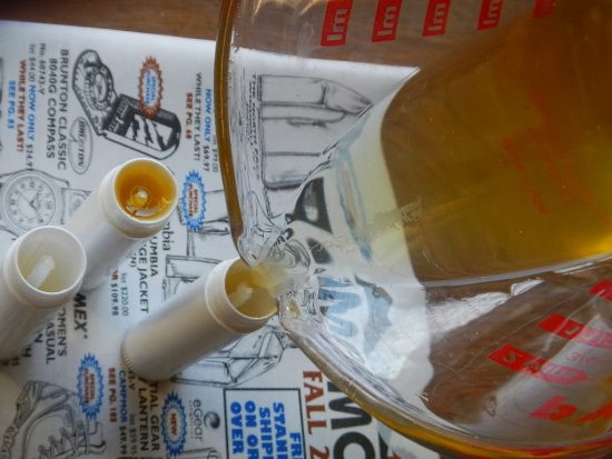 Pouring homemade lip balm into tubes with an easy DIY recipe